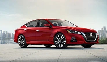 2023 Nissan Altima in red with city in background illustrating last year's 2022 model in Coastal Nissan in Norwell MA
